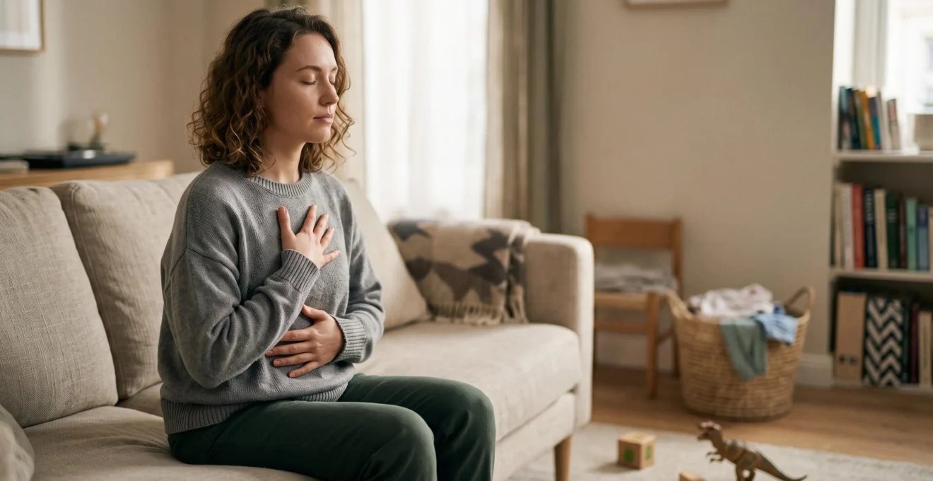 Femme assise dans un salon lumineux, une main posée sur le ventre, pratiquant une respiration abdominale calme malgré l'agitation domestique en arrière-plan